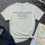 Bay colored Comfort Colors t-shirt with 'Washington Heights' text with coordinates and 'New York City' on a dark surface with a map and denim jacket.