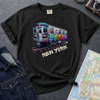 Black Comfort Colors t-shirt with a graffiti train graphic and 'New York' text on a dark surface with a map and jacket.