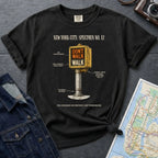 Black Comfort Colors t-shirt with a graphic design of a vintage intersection crossing sign and text, placed on a dark surface with a denim jacket and a map.