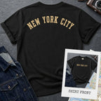 Black Comfort Colors t-shirt with 'New York City' print on a textured surface with a camera and denim jacket.