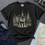 Blac Comfort Colors t-shirt with a Golden Doodle and cityscape graphic on a dark surface with a denim jacket and a map.