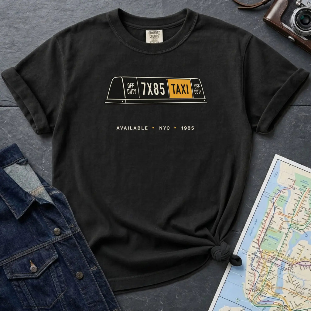 Black Comfort Colors t-shirt with NYC taxi-themed graphic on a gray surface with a denim jacket and a map.