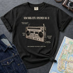 Black Comfort Colors t-shirt with a graphic of a boombox and text on a dark surface with a denim jacket and map.