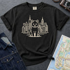 Black Comfort Colors t-shirt featuring a minimalist Shiba Inu graphic in front of the New York City skyline on a dark surface with a denim jacket and a map.