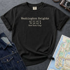 Black Comfort Colors t-shirt with 'Washington Heights' text with coordinates and 'New York City' on a dark surface with a map and denim jacket.