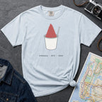 Light blue Comfort Colors t-shirt with a piragua graphic and text, placed on a dark surface with a map and denim jacket.