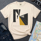 Beige t-shirt with a graphic design of a train station platform, denim jacket, and map on a dark surface