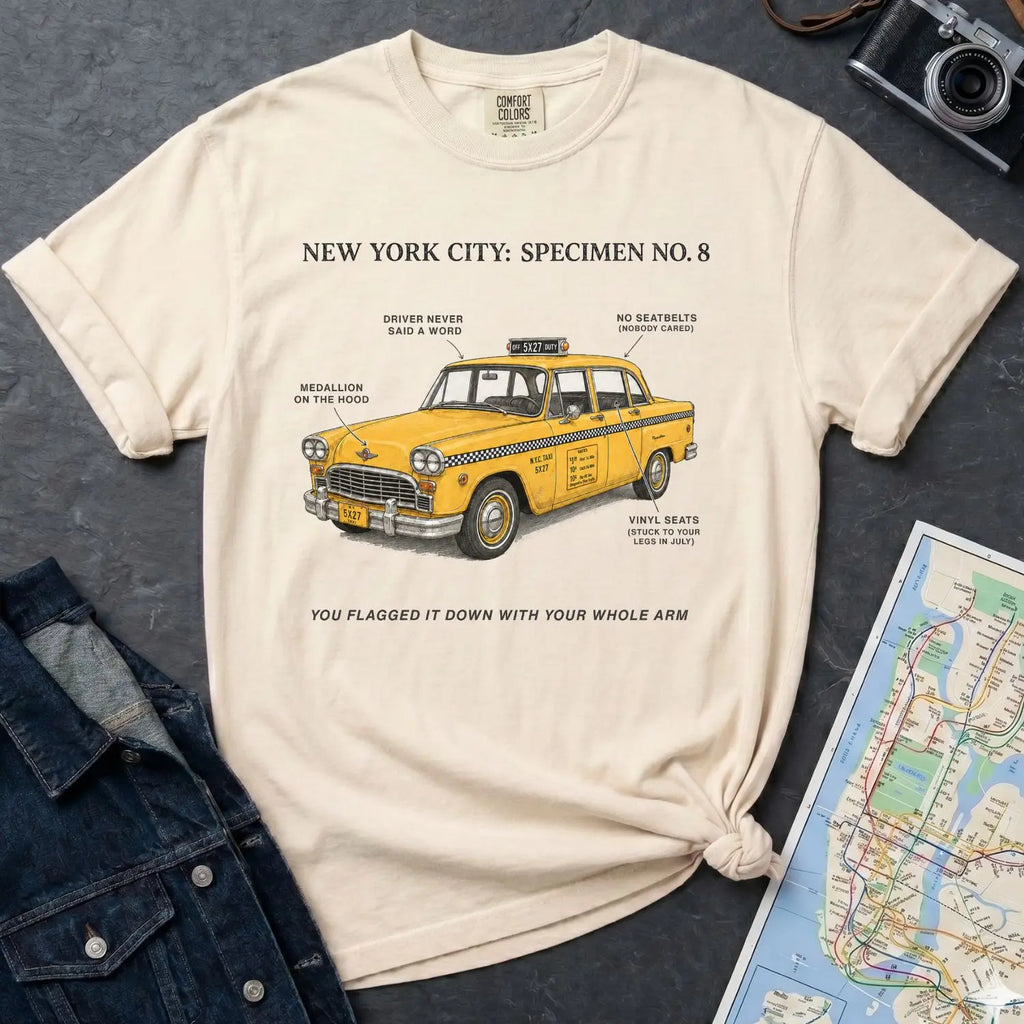 Ivory Comfort Colors t-shirt with yellow taxi graphic and text on a dark surface with denim jacket and map.