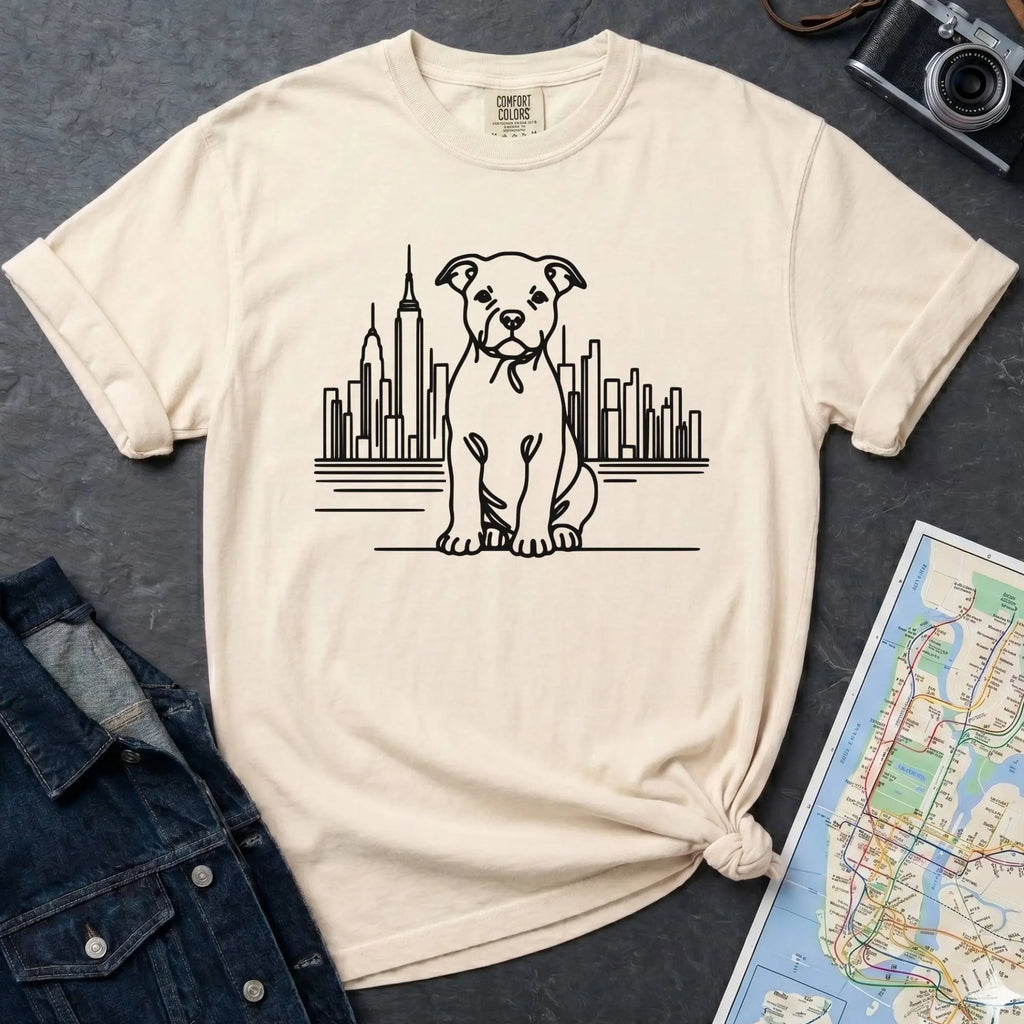 Ivory t-shirt with a Pitbull dog and cityscape design on a dark surface with jeans and a map.