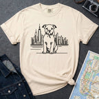 Ivory t-shirt with a Pitbull dog and cityscape design on a dark surface with jeans and a map.