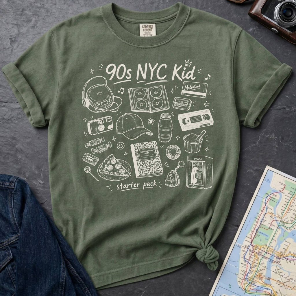 Moss t-shirt with '90s NYC Kid' graphic design on a dark surface with a denim jacket and a map.