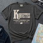 Pepper colored Comfort Colors t-shirt with Korvettes in large distressed vintage lettering, Discount Department Store and New York City, Est. 1948 below, with a price tag illustration, displayed flat with a denim jacket and subway map.