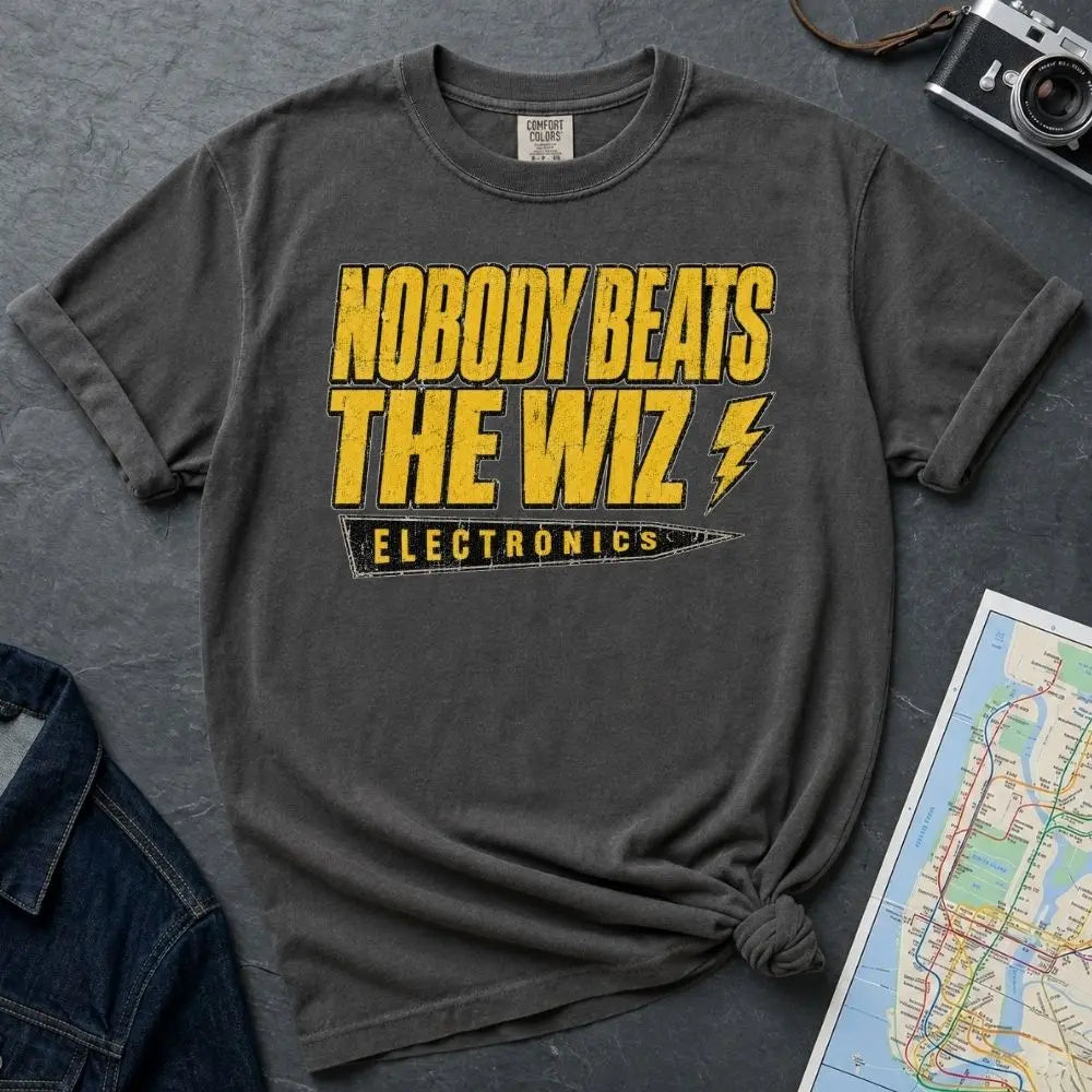 Pepper-colored Comfort Colors T-shirt with yellow and black The Wiz Electronics NYC front print, styled with denim jacket, camera, and subway map