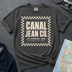 Pepper colored Comfort Colors T-shirt with ivory Canal Jean Co. NYC front print, styled with denim jacket, camera, and subway map.