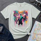 Bay colored t-shirt with a graphic of a person spray painting a colorful mural on a brick wall.
