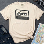 Ivory Comfort Colors t-shirt with a cassette tape graphic on a gray surface with denim jacket and map.