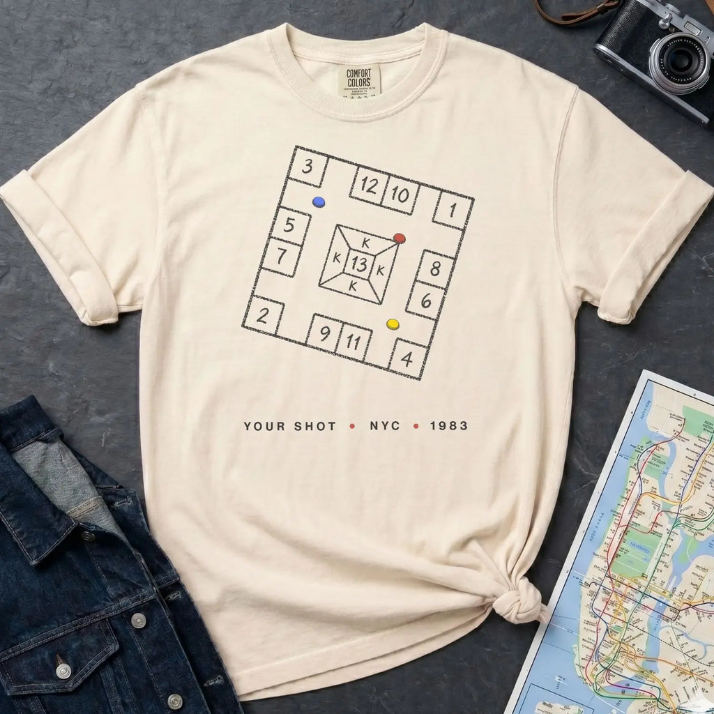Ivory Comfort Colors t-shirt with New York City skelzies design on a gray surface with denim jacket and map.