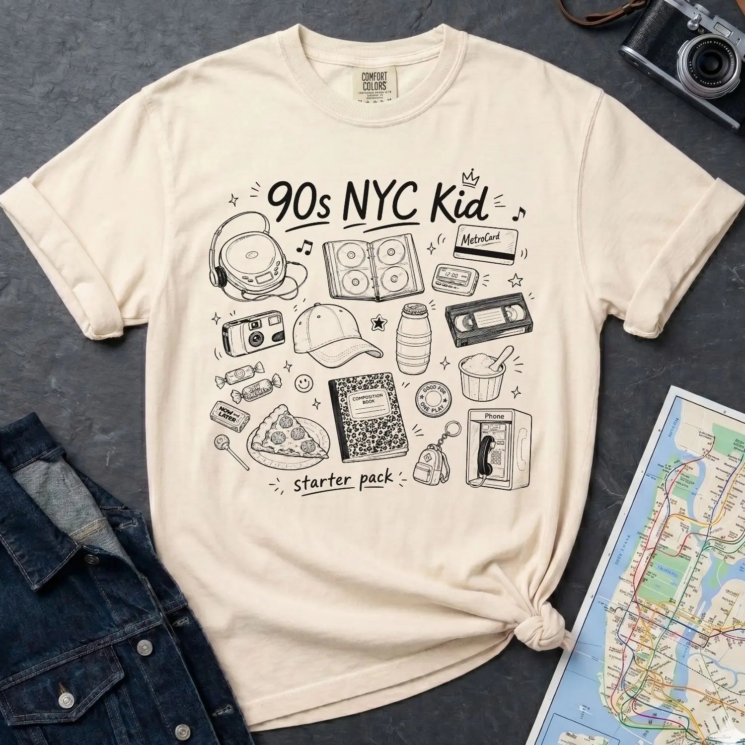 Ivory Comfort Colors t-shirt with '90s NYC Kid' graphic design on a dark surface with denim jacket and map.