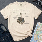 Ivory Comfort Colors T-shirt with NYC sneakers on wire specimen front print, styled with denim jacket, camera, and subway map
