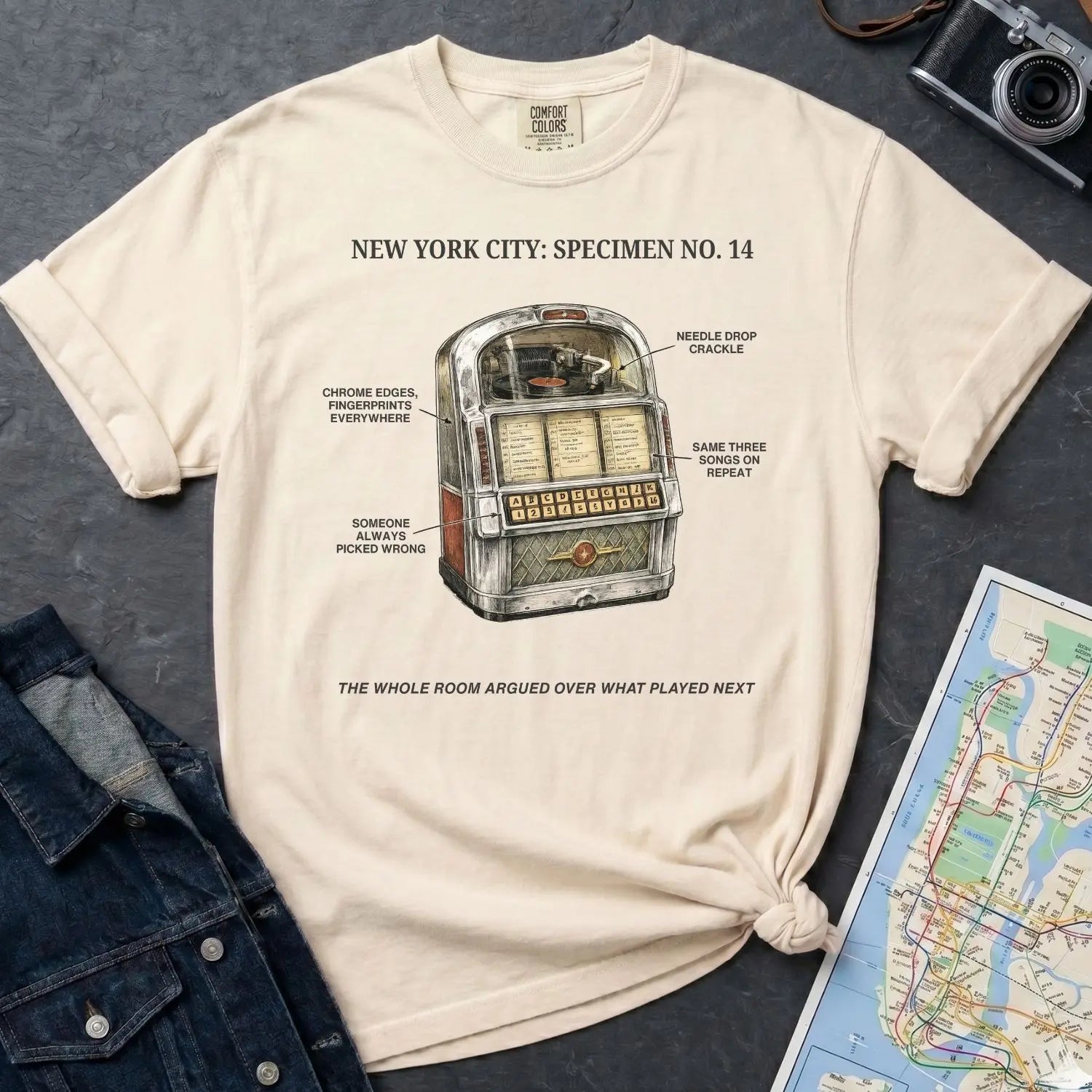 Ivory Comfort Colors t-shirt with a vintage jukebox graphic and text on a dark surface with a denim jacket and a map.