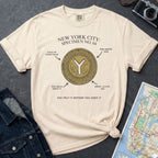 Ivory Comfort Colors t-shirt with New York City vintage token design on a gray surface with denim jacket and map.