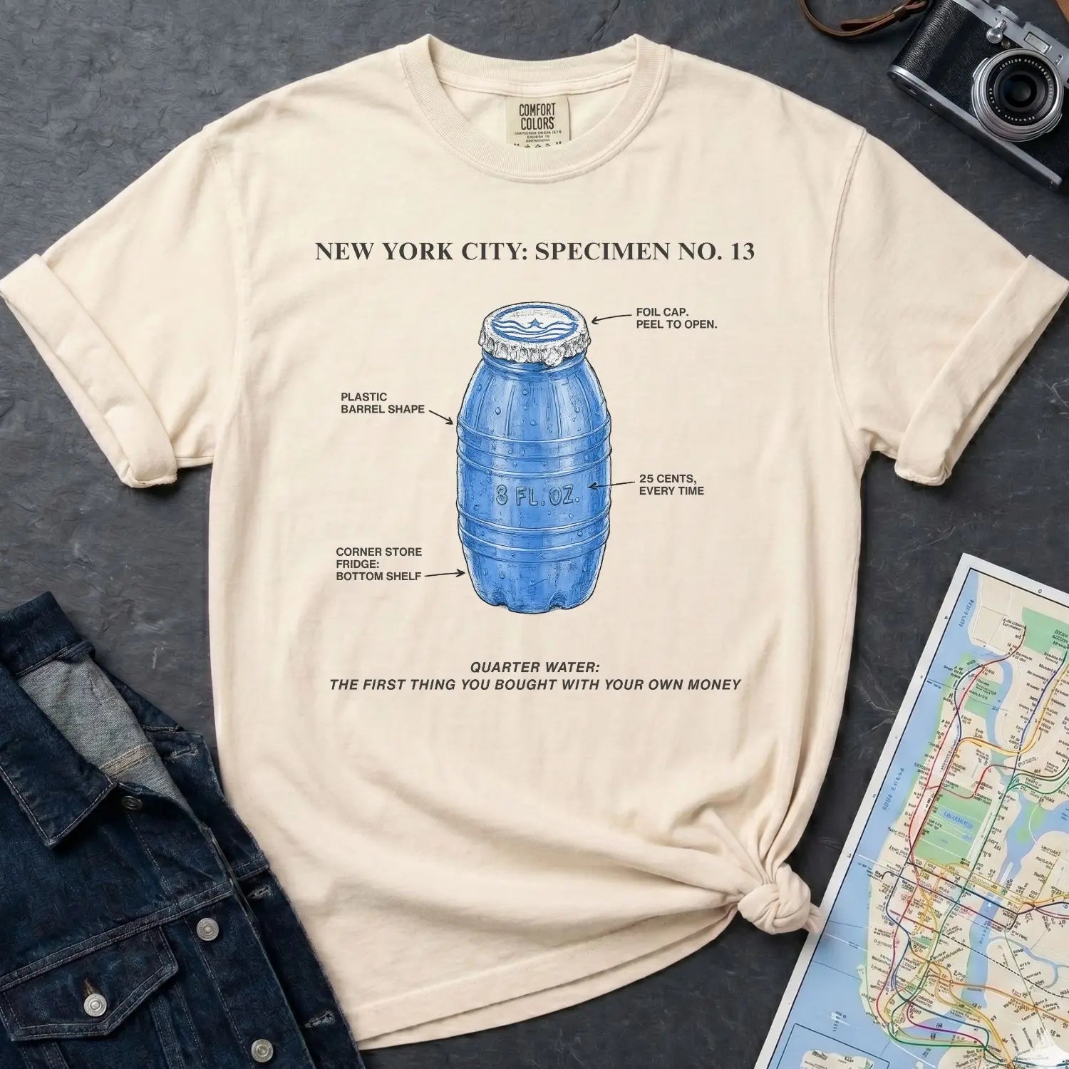 Ivory Comfort Colors t-shirt with blue Quarter Water graphic and text on a dark surface with denim jacket and map.