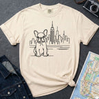 Ivory Comfort Colors t-shirt with a French Bulldog and cityscape design on a gray surface with a map and denim jacket.