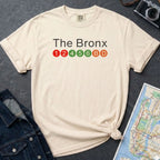 Ivory Comfort Colors t-shirt with 'The Bronx' text and subway line design on a dark surface with a denim jacket and a map.