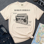 Ivory Comfort Colors t-shirt with a graphic of a boombox and text on a dark surface with a denim jacket and map.