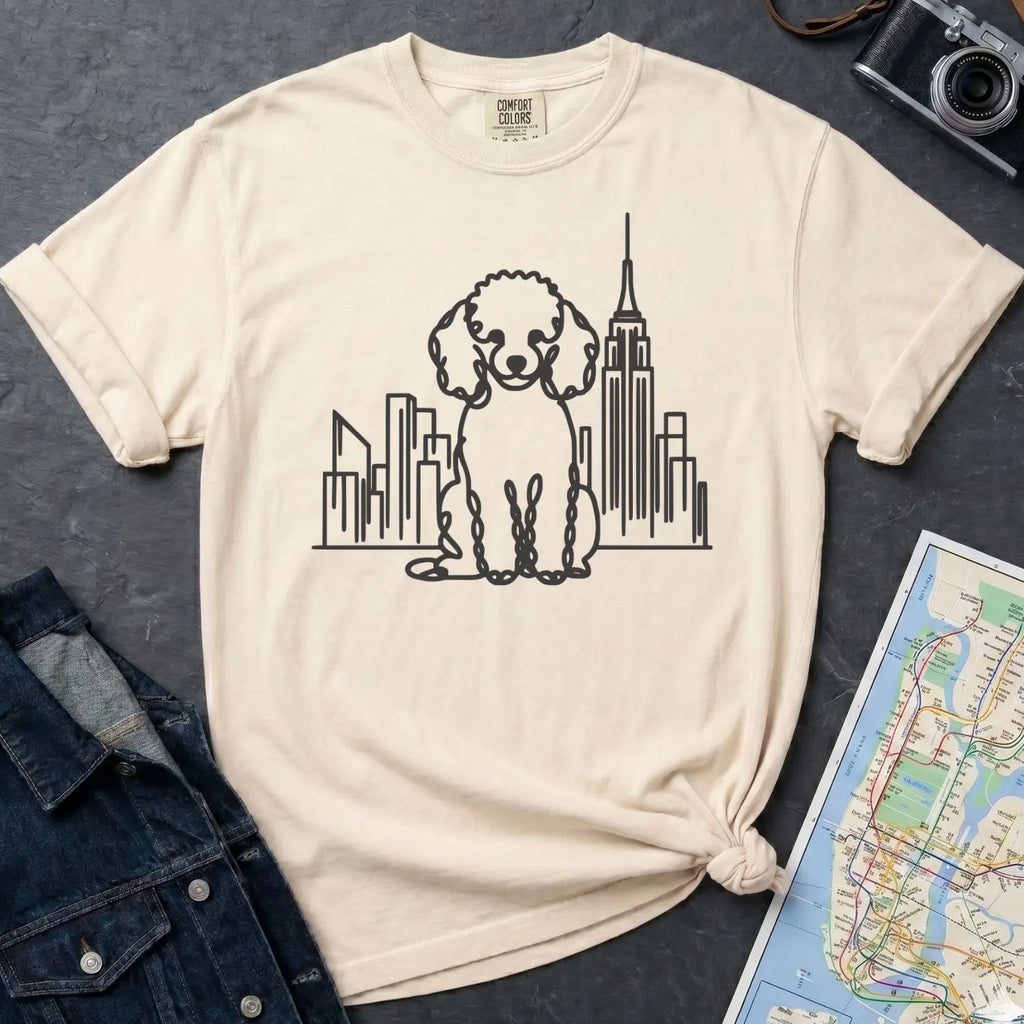 Ivory Comfort Colors t-shirt with a Poodle and cityscape design on a dark surface with a denim jacket and a map.