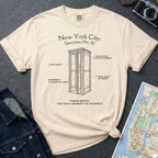 Ivory Comfort Colors t-shirt with phone booth design and text on a dark surface with denim jacket and map.