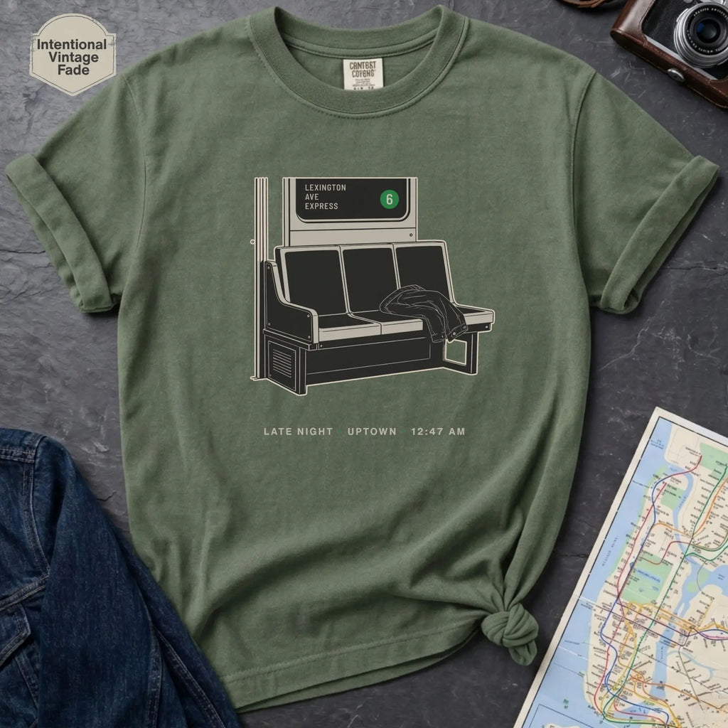Moss colored t-shirt with a graphic design of a train interior and text on a dark surface.