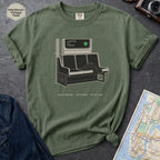 Moss colored t-shirt with a graphic design of a train interior and text on a dark surface.