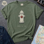 Green t-shirt with a fire hydrant graphic on a dark surface with a map and jeans.