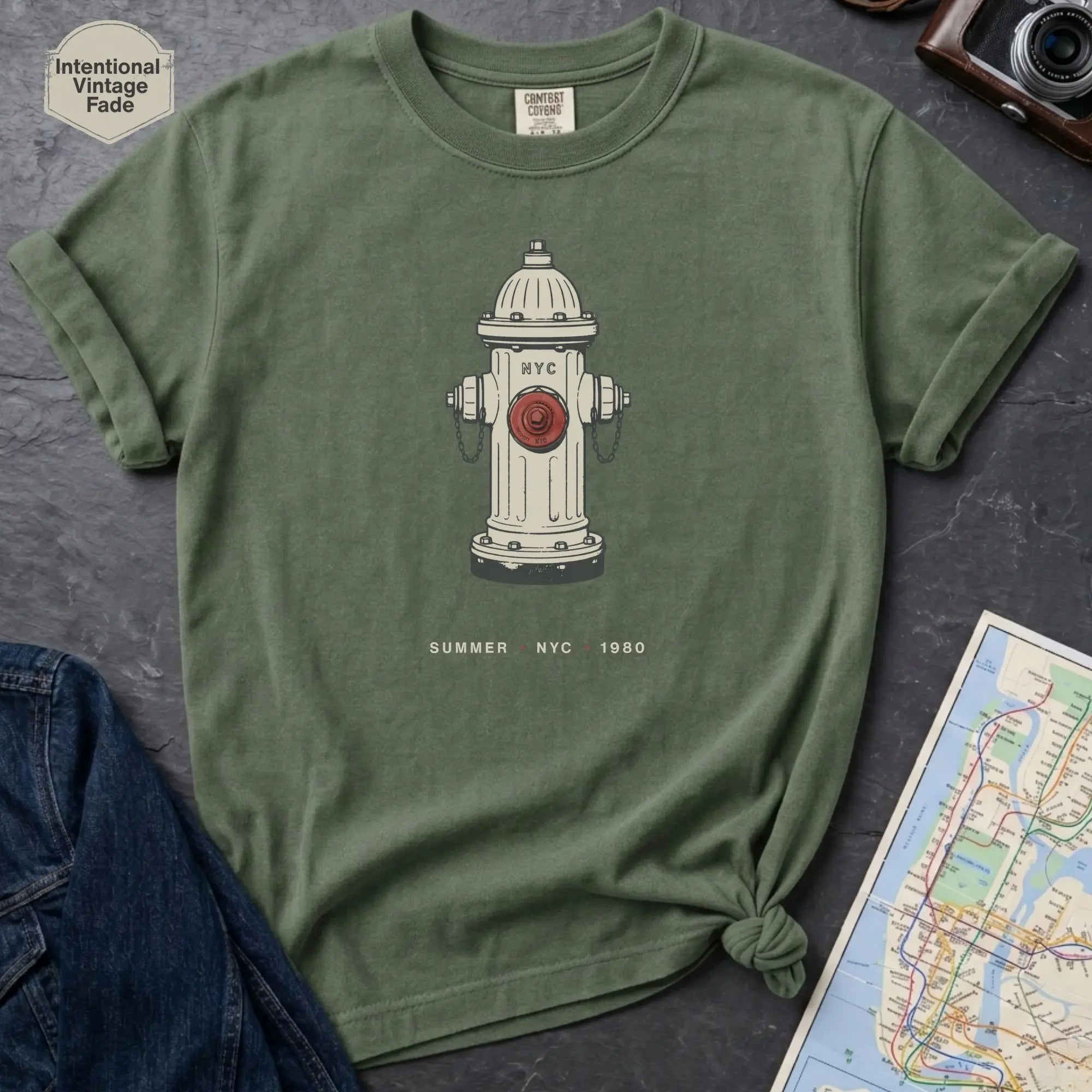 Green t-shirt with a fire hydrant graphic on a dark surface with a map and jeans.
