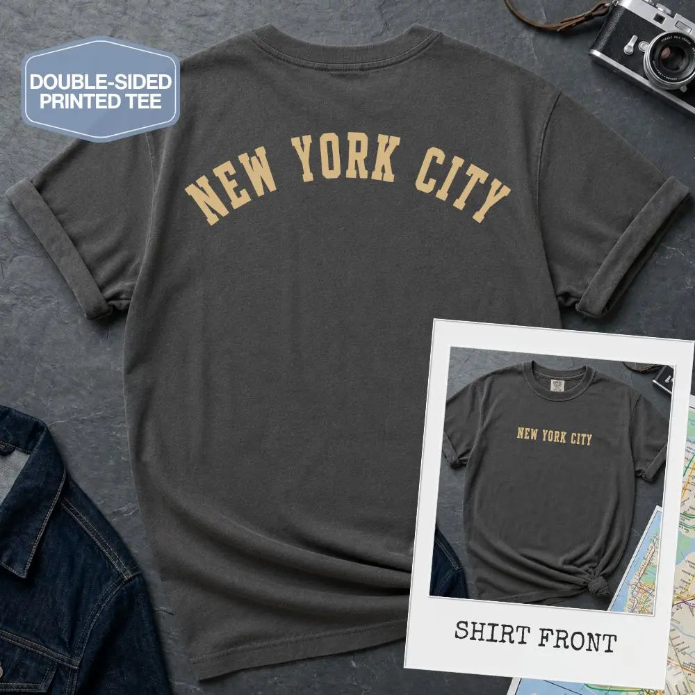 Pepper colored Comfort Colors t-shirt with 'New York City' print on a textured surface with a camera and denim jacket.