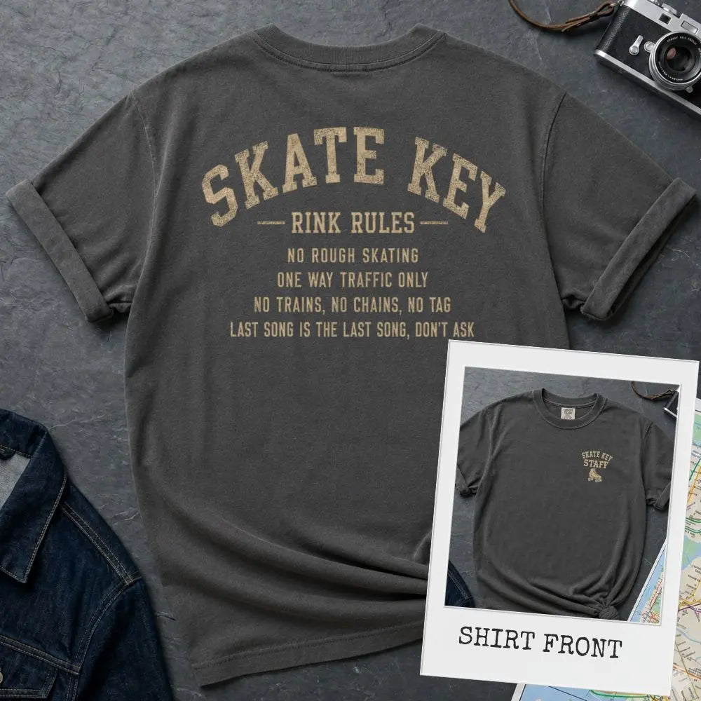 Pepper colored Comfort Colors t-shirt, back view, with Skate Key Rink Rules printed in distressed gold lettering. Rules read: No Rough Skating, One Way Traffic Only, No Trains No Chains No Tag, Last Song Is The Last Song Don't Ask. Inset shows shirt front with Skate Key Staff logo on chest.