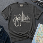 Pepper colored t-shirt with a French Bulldog and cityscape design on a gray surface with a denim jacket and a map.