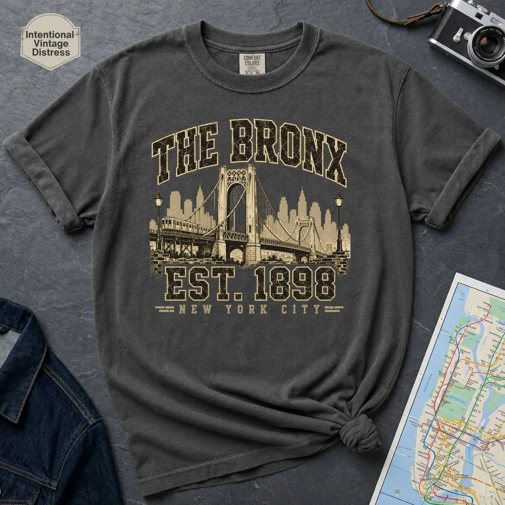 Pepper colored t-shirt with 'The Bronx Est. 1898' design on a dark surface with a map and a denim jacket.
