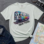 Bay colored t-shirt with a colorful train graphic and 'New York' text on a gray surface with a map and denim jacket.