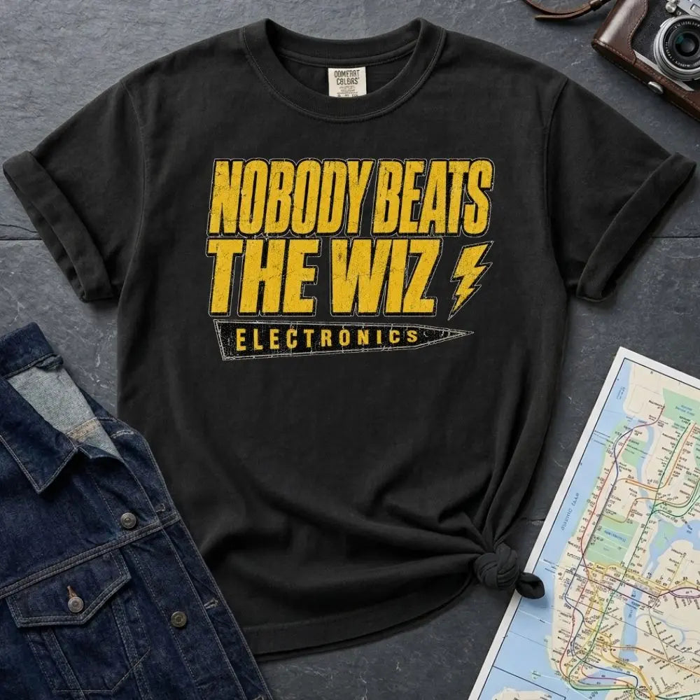 Black Comfort Colors T-shirt with yellow and black The Wiz Electronics NYC front print, styled with denim jacket, camera, and subway map