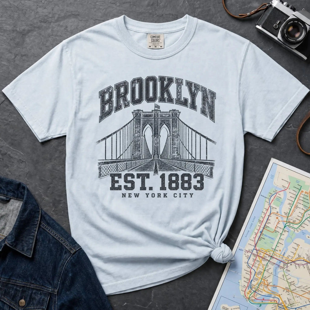 Light blue Vintage-style Brooklyn NYC graphic t-shirt on a Bay colored Comfort Colors cotton shirt, featuring the Brooklyn Bridge and “Brooklyn Est. 1883” text.