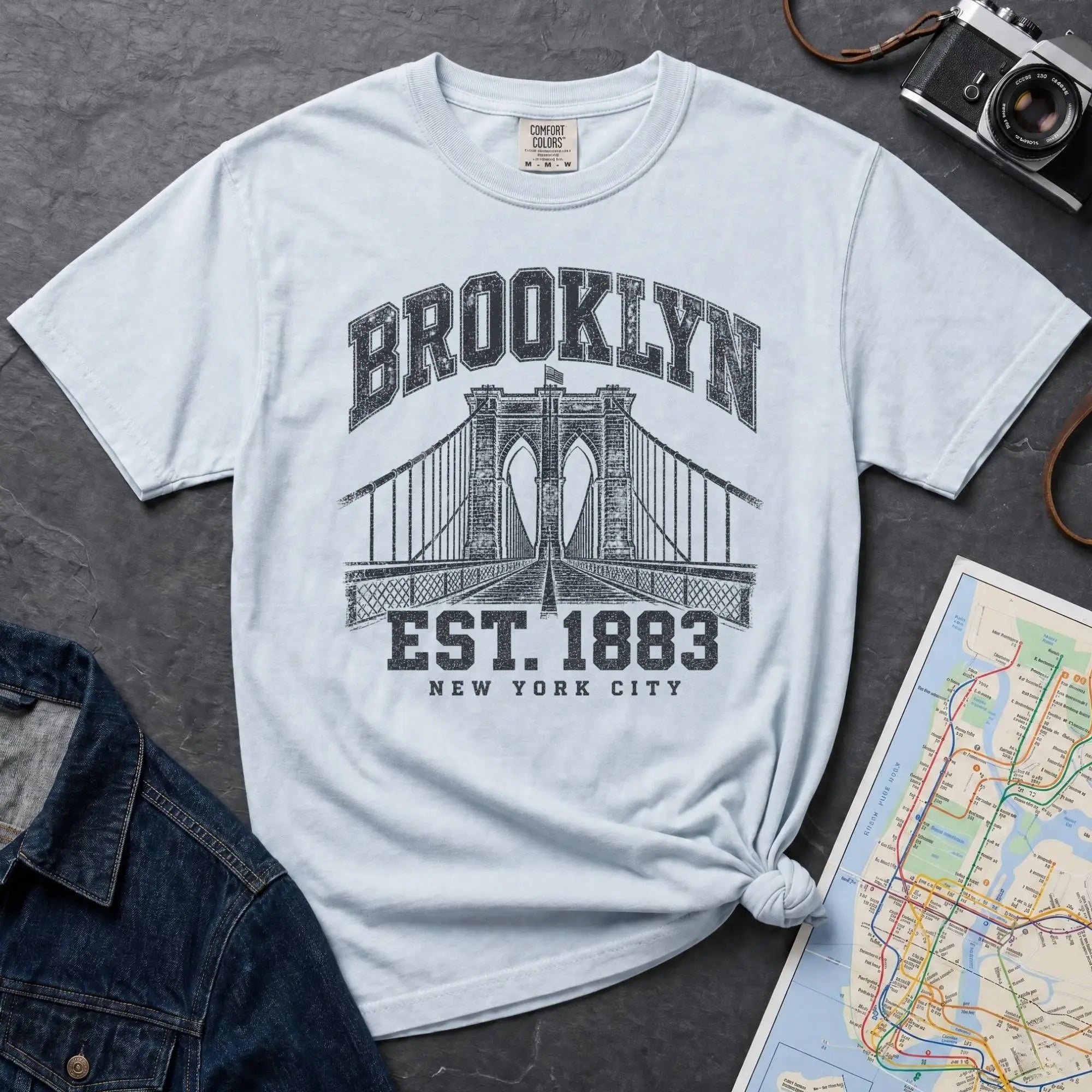 Light blue Vintage-style Brooklyn NYC graphic t-shirt on a Bay colored Comfort Colors cotton shirt, featuring the Brooklyn Bridge and “Brooklyn Est. 1883” text.