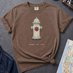 Brown t-shirt with a fire hydrant graphic on a gray surface with a map and jacket.