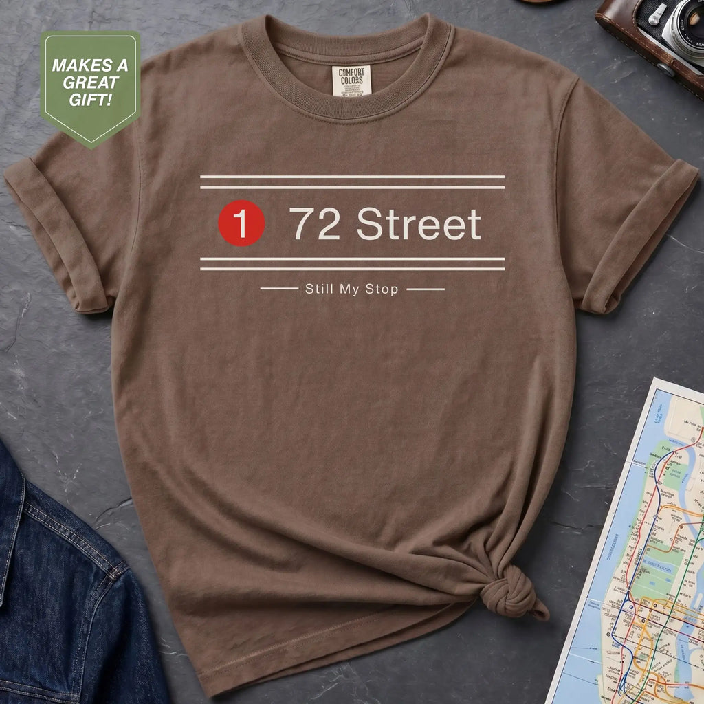 Brown t-shirt with '72 Street' design on a gray surface with a map and jacket.