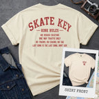 Ivory Comfort Colors t-shirt, back view, with Skate Key Rink Rules printed in distressed red lettering. Rules read: No Rough Skating, One Way Traffic Only, No Trains No Chains No Tag, Last Song Is The Last Song Don't Ask. Inset shows shirt front with Skate Key Staff logo on chest.