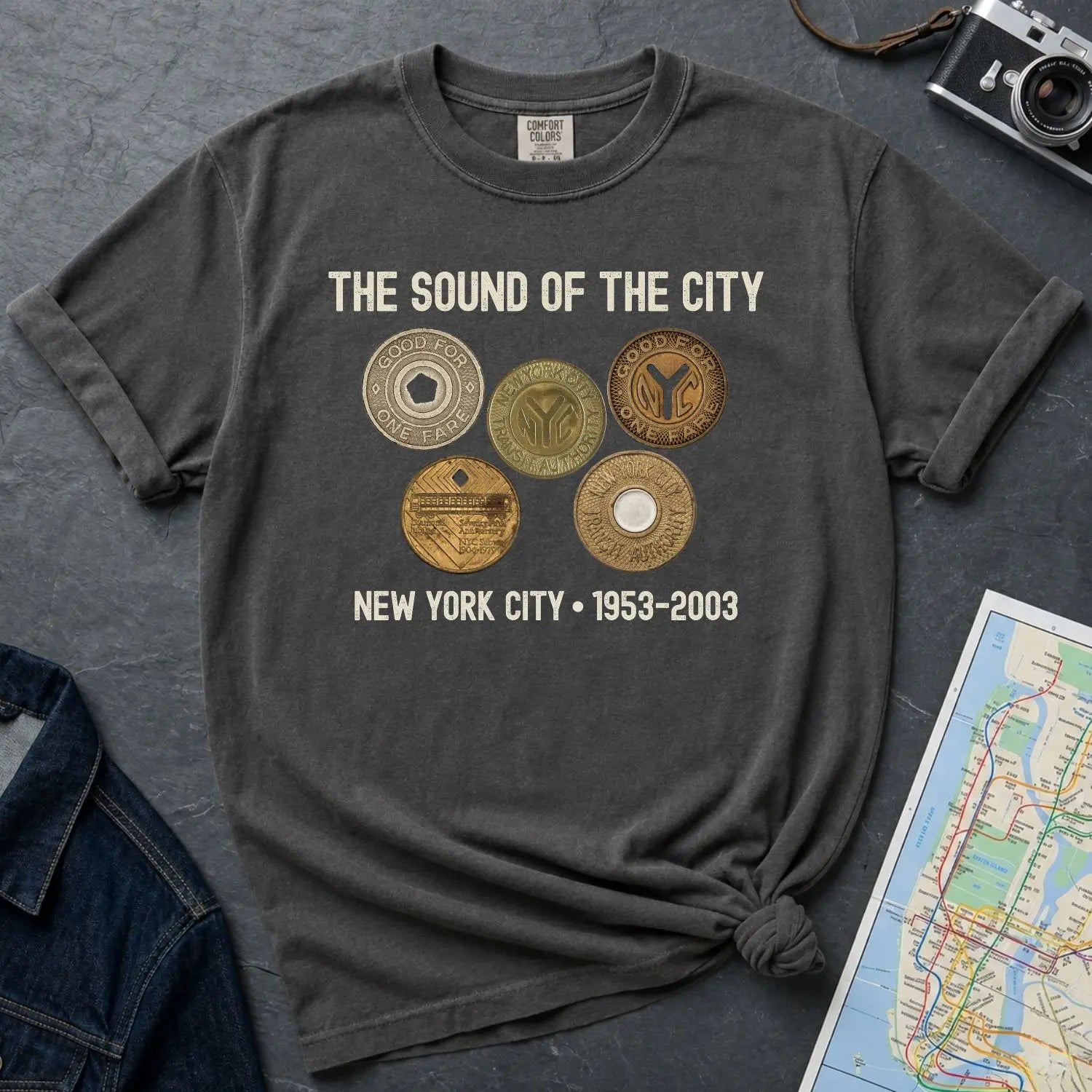 Pepper colored Comfort Colors t-shirt with 'The Sound of the City' design featuring vintage coins on a textured surface with a camera and map.