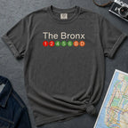 Pepper colored Comfort Colors t-shirt with 'The Bronx' text and subway line design on a dark surface with a map and camera.