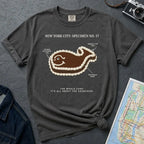 Pepper-colored Comfort Colors T-shirt with NYC whale cake specimen front print, styled with denim jacket, camera, and subway map