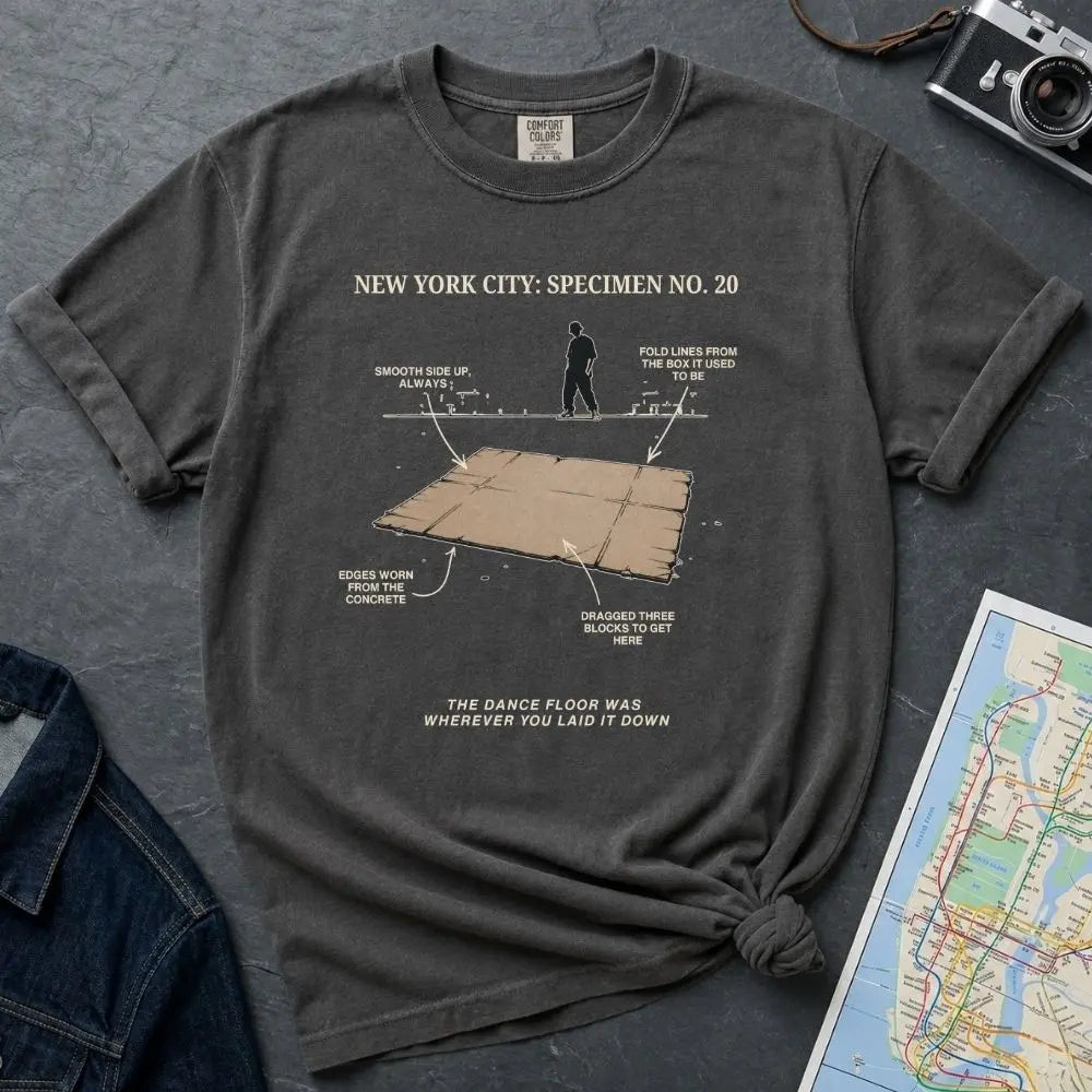 Pepper colored Comfort Colors T-shirt with NYC breakdance cardboard specimen front print, styled with denim jacket, camera, and subway map